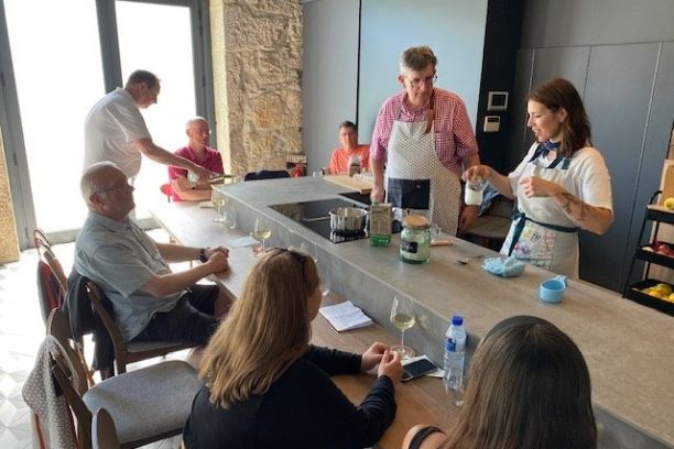 People sitting and standing around a kitchen island during a cooking class.