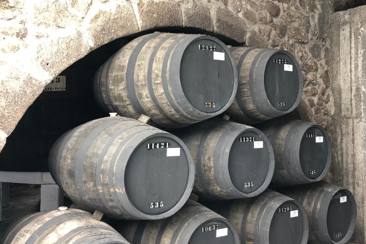 Stacked barrels in stone cellar with archway.