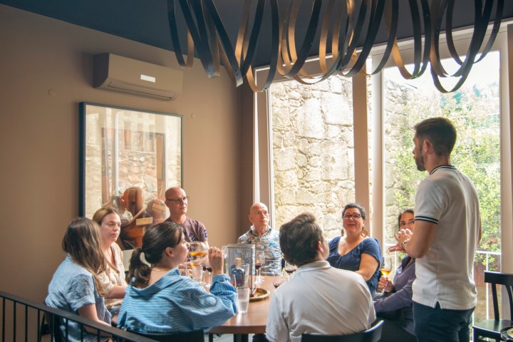 People seated at a round table in a room with a modern light fixture above them.