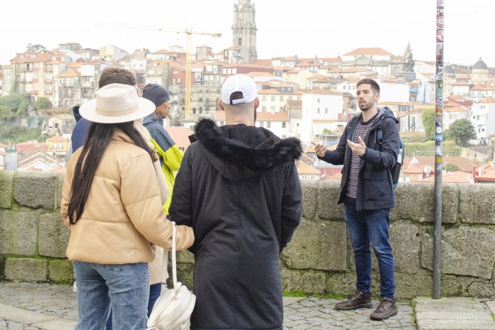 Tour guide speaking to a group of people in front of a cityscape with a tower.