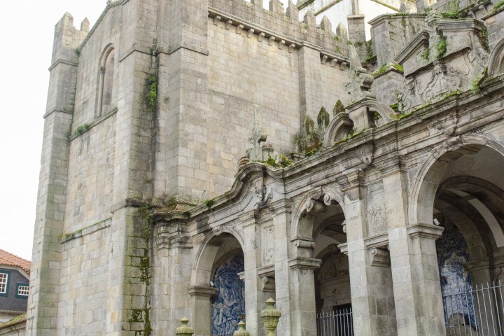 Exterior of a stone cathedral with archways and crenellated walls.